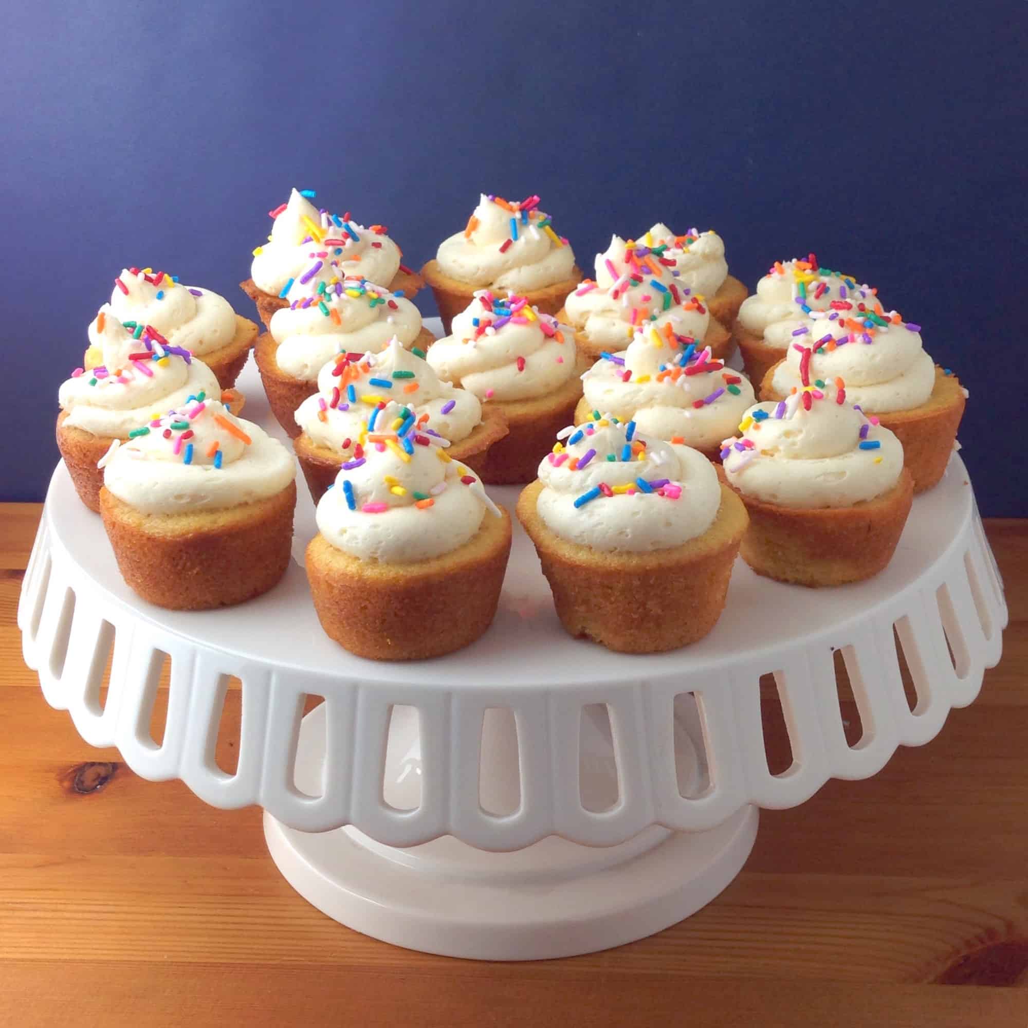 mini vanilla cupcakes sitting on a cake stand