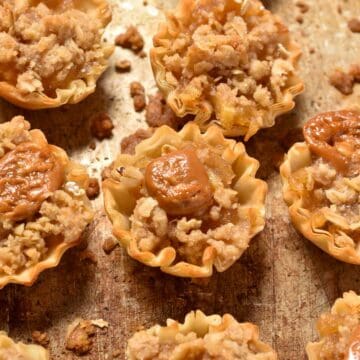 apple filling in a phyllo cup with streusel topping and caramel.
