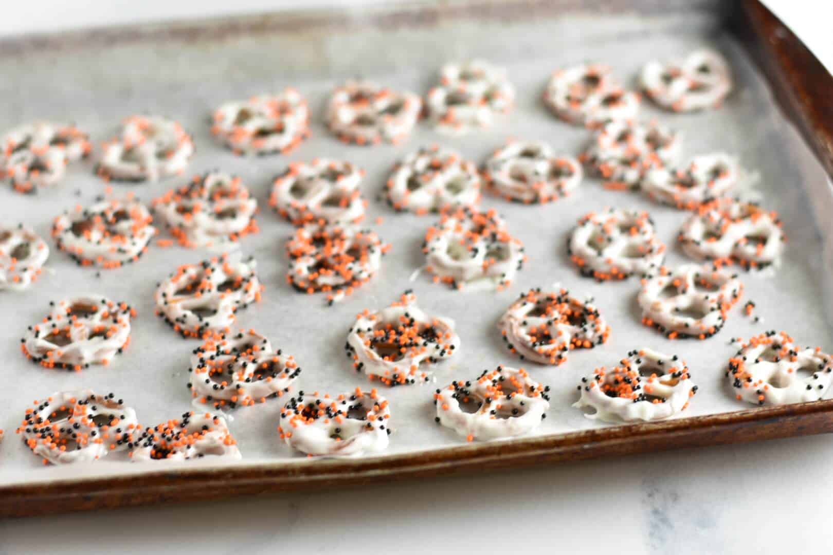Halloween pretzel treats on baking sheet with Halloween sprinkles 