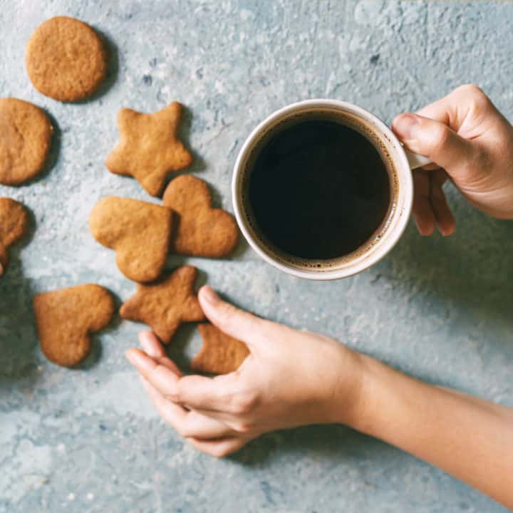 hand holding coffee cup with cookies