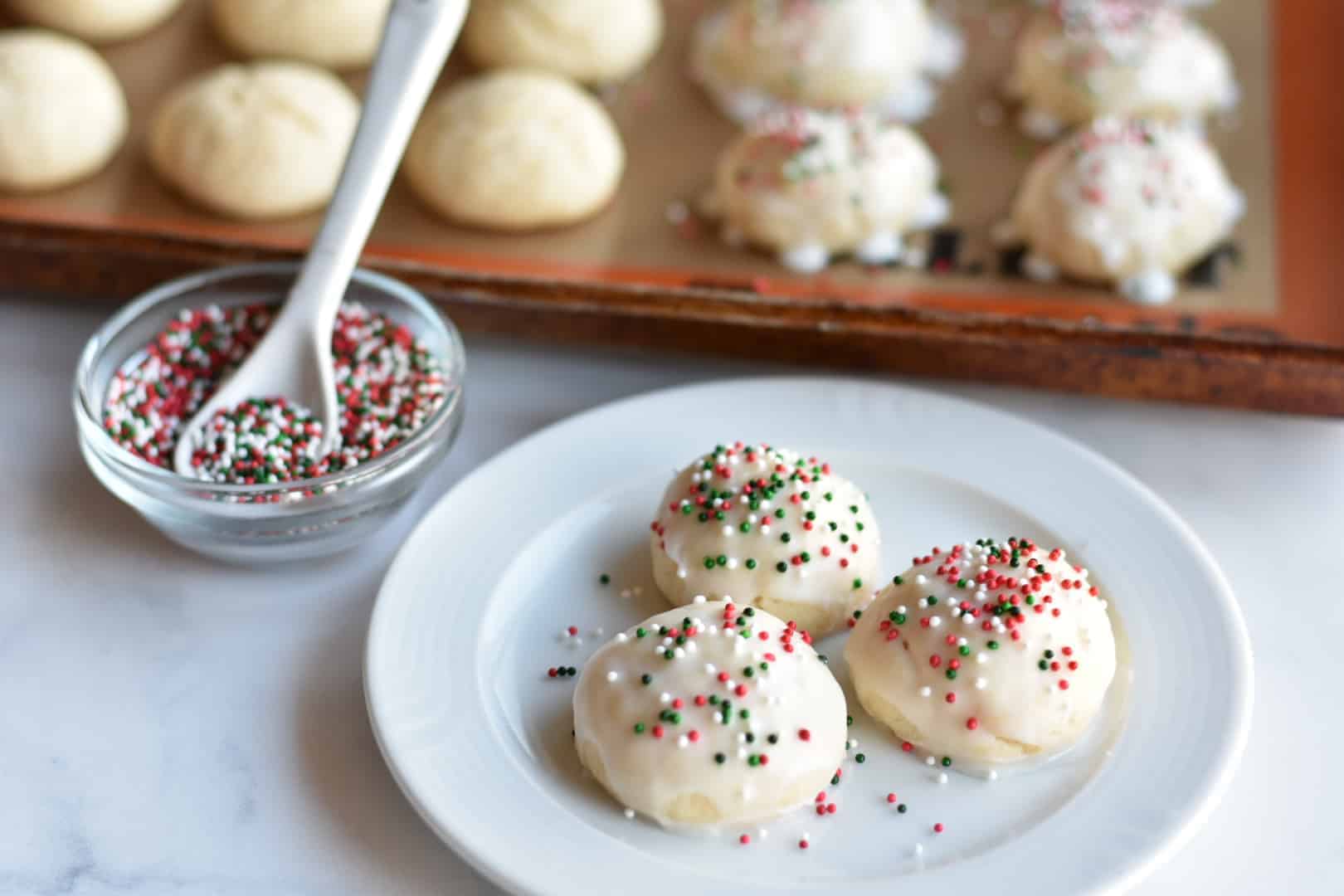 Italian Christmas cookies on a white plate with sprinkles in the background