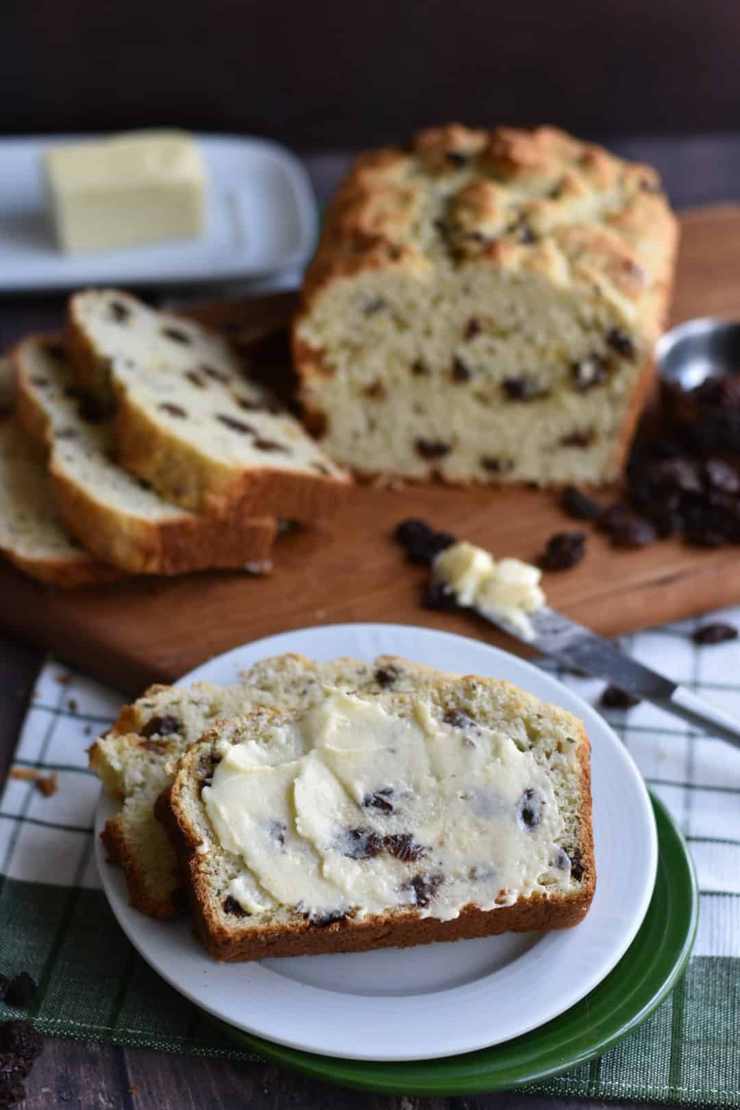 closeup of Irish Soda Bread slice with butter and loaf in background