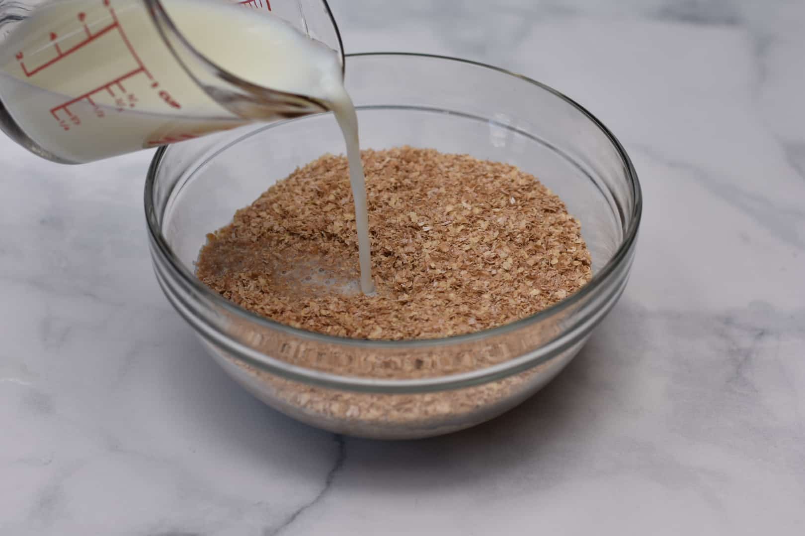 skim milk being poured into bowl of oat bran
