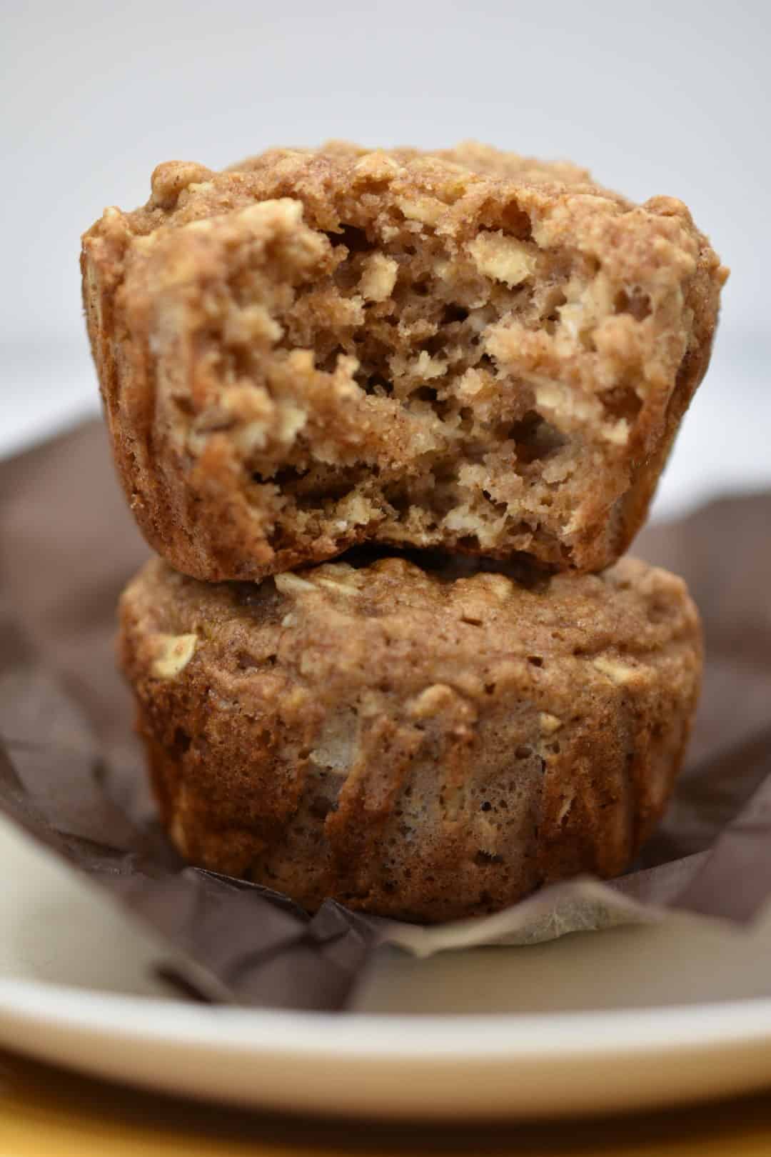 close up of oatmeal applesauce muffins stacked on top of each other with a bite out