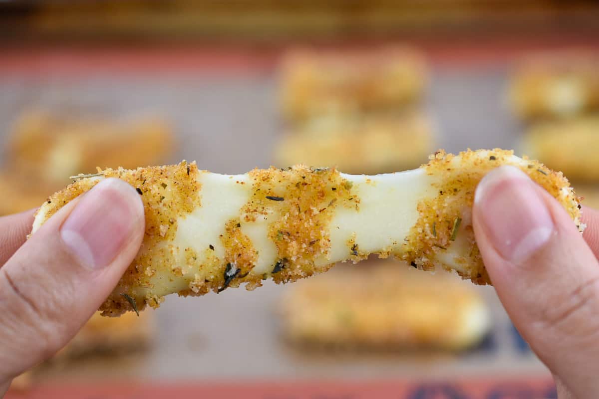 two fingers pulling apart a warm baked mozzarella stick