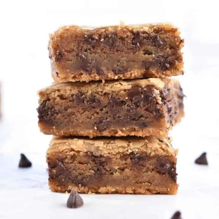closeup image of three stacked chocolate chip cookie butter blondies