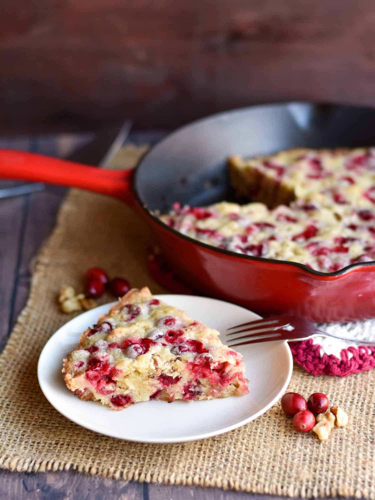 closeup of almond cranberry cake with cast-iron skillet in background
