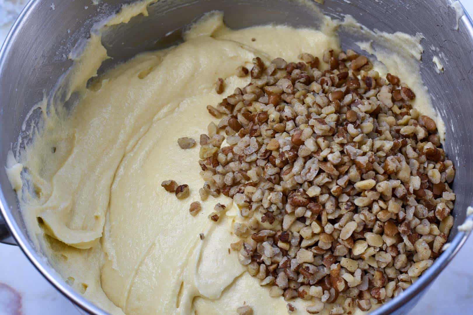 cake batter in mixing bowl with black walnuts
