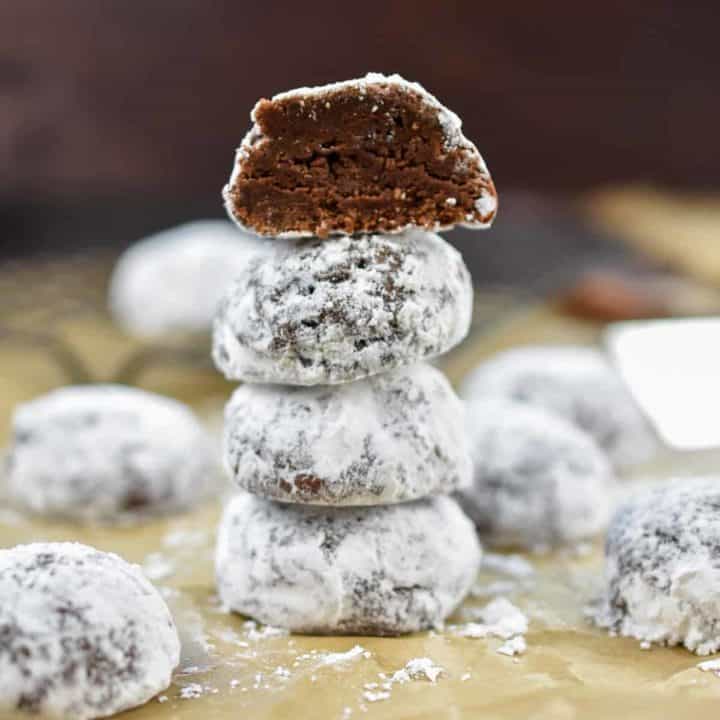 closeup image of four chocolate snowball cookies stacked on top of each other.