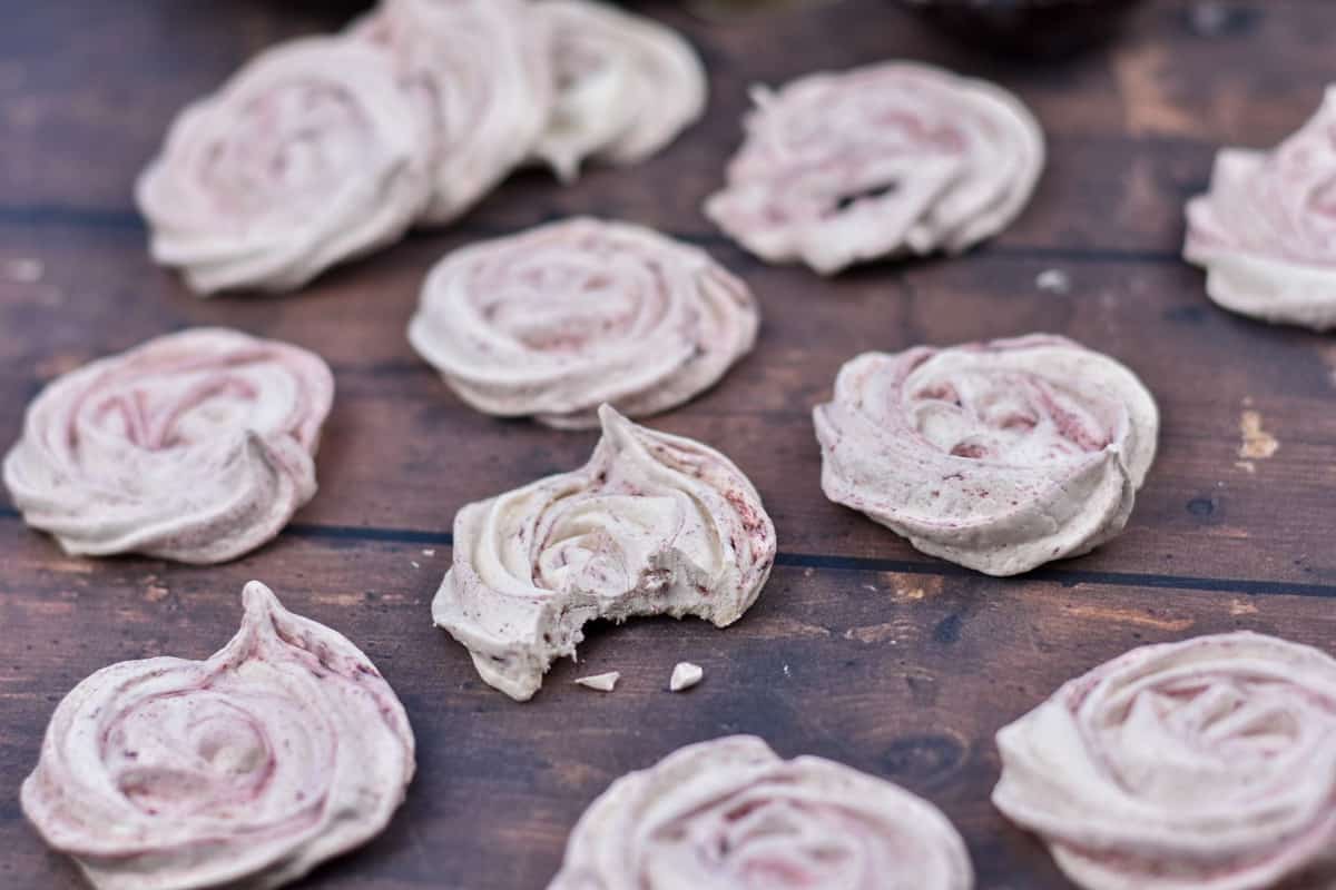 meringue cookies on table with a bite out of one cookie.