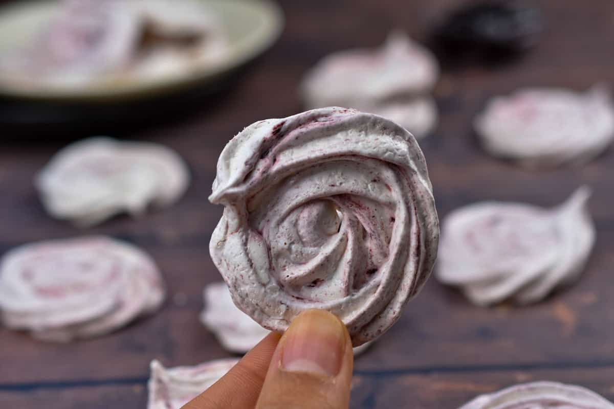 closeup of a hand holding a meringue cookie.