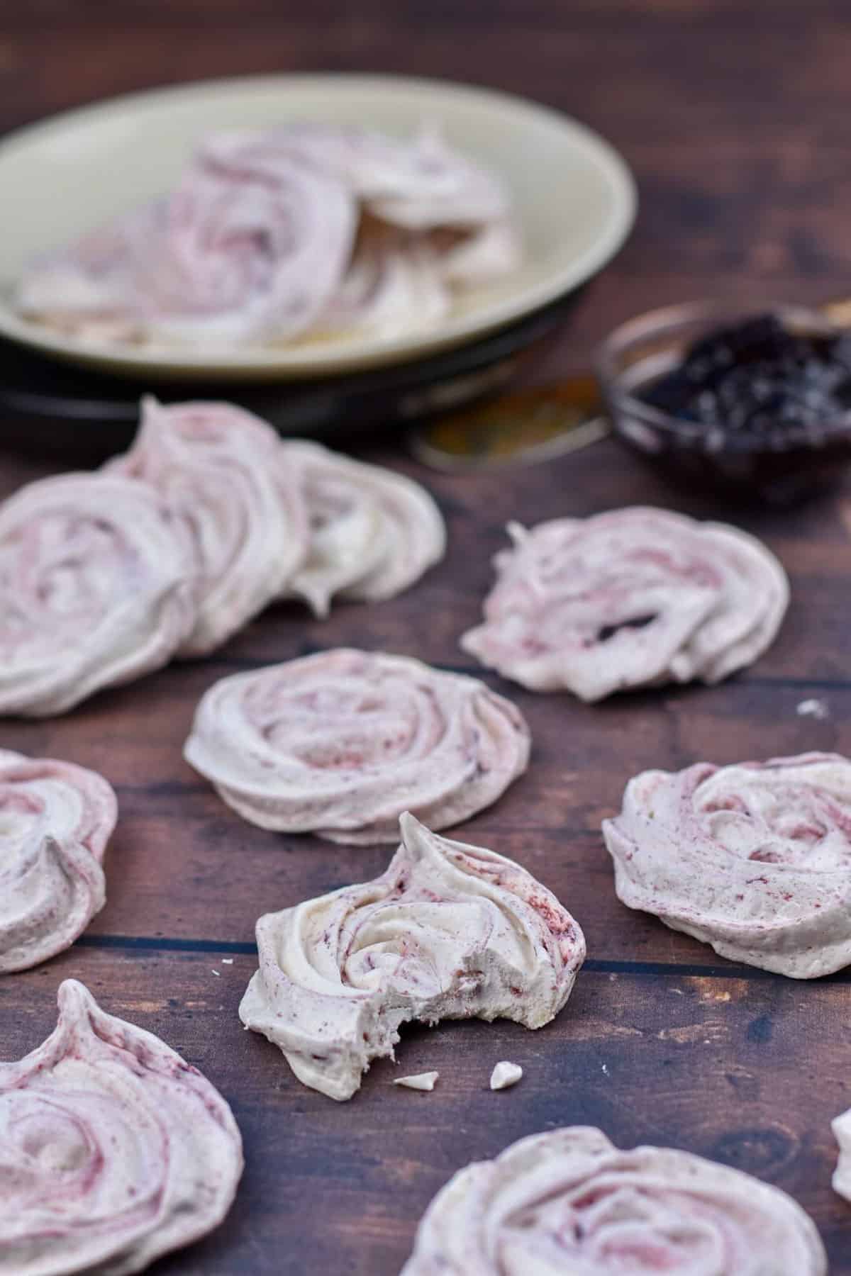 meringue cookies on table with a small bowl of blackberry jam.