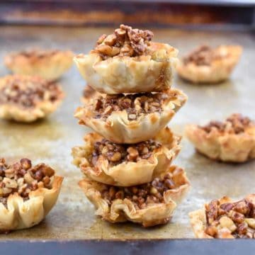 closeup of four mini pecan tarts stacked on top of each other