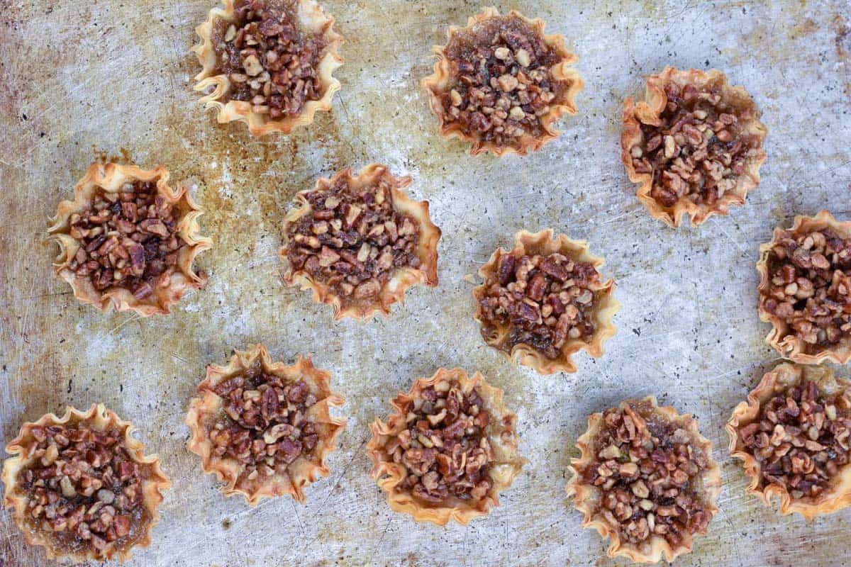 overhead shot of pecan tarts on baking sheet.