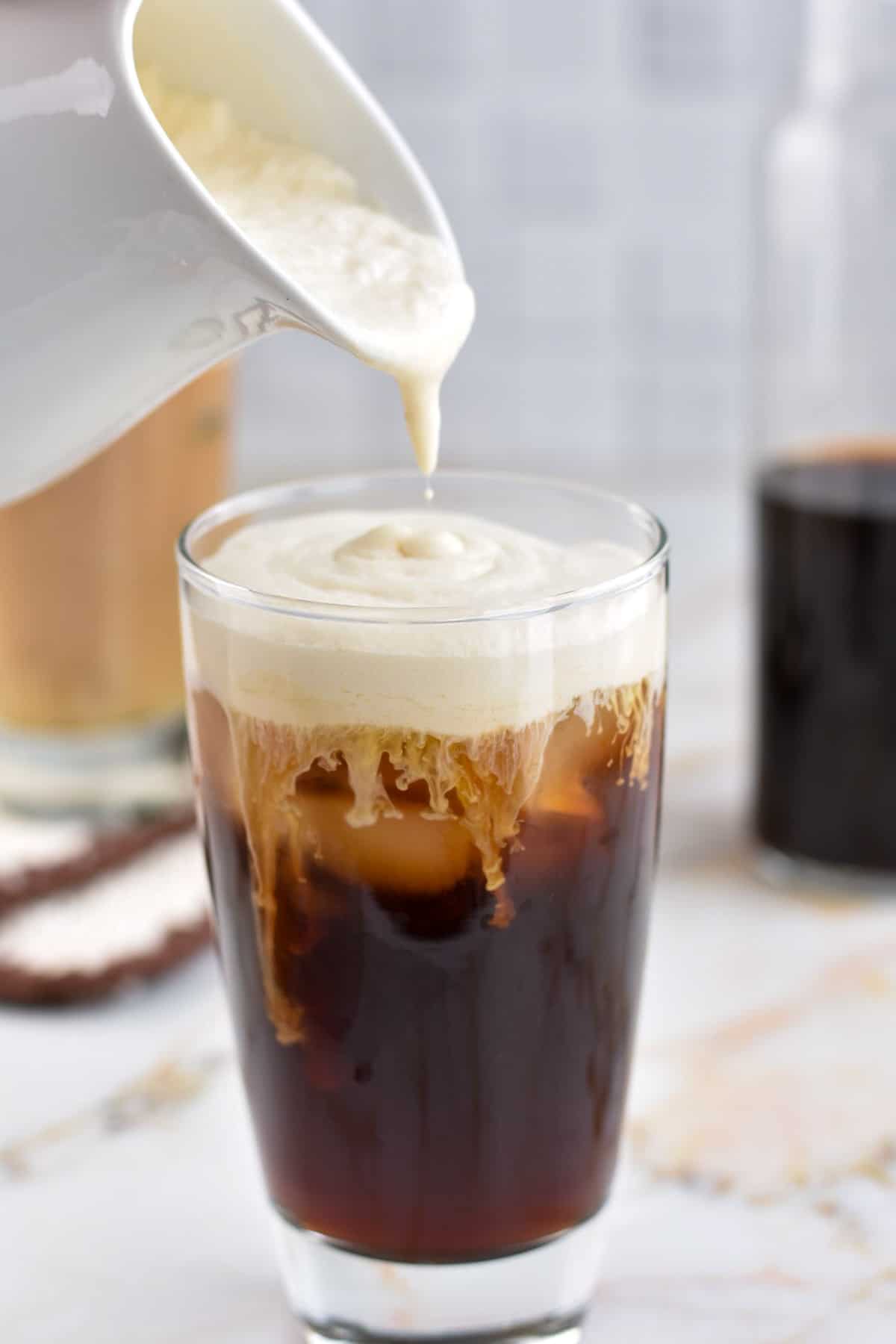 cold brew coffee in cup with irish cream being poured into the glass