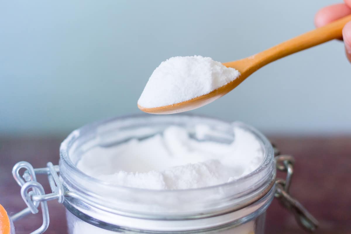spoon scooping baking soda out of a clear mason jar