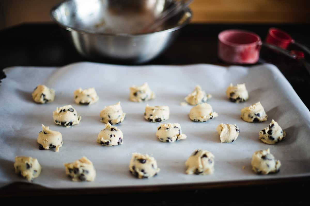 chocolate chip cookie dough sitting on parchment lined baking sheet