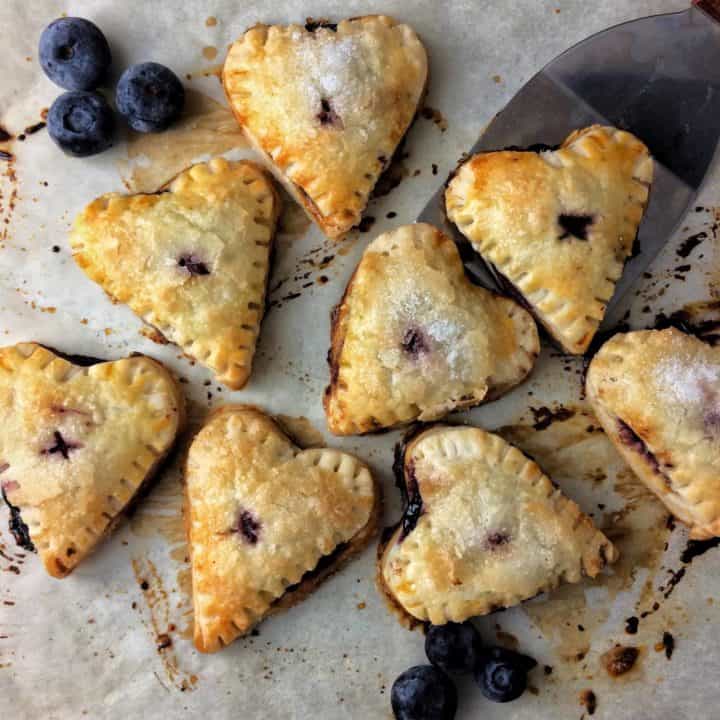 overhead shot of blueberry hand pies sitting on a baking sheet