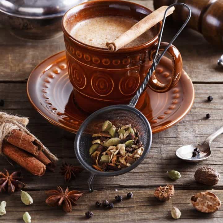 chai tea in a mug with spices surrounding.