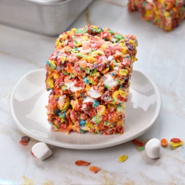 two fruity pebbles treats stacked on a white plate.