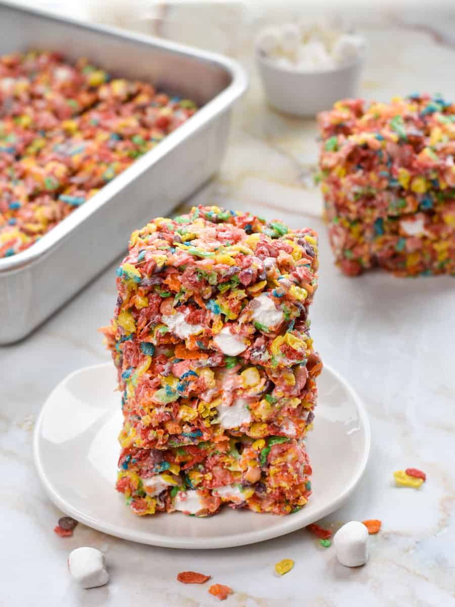 three fruity pebbles treats stacked on top of each other on a white plate. 