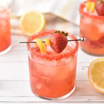 strawberry vodka in clear glass with lemon garnish.