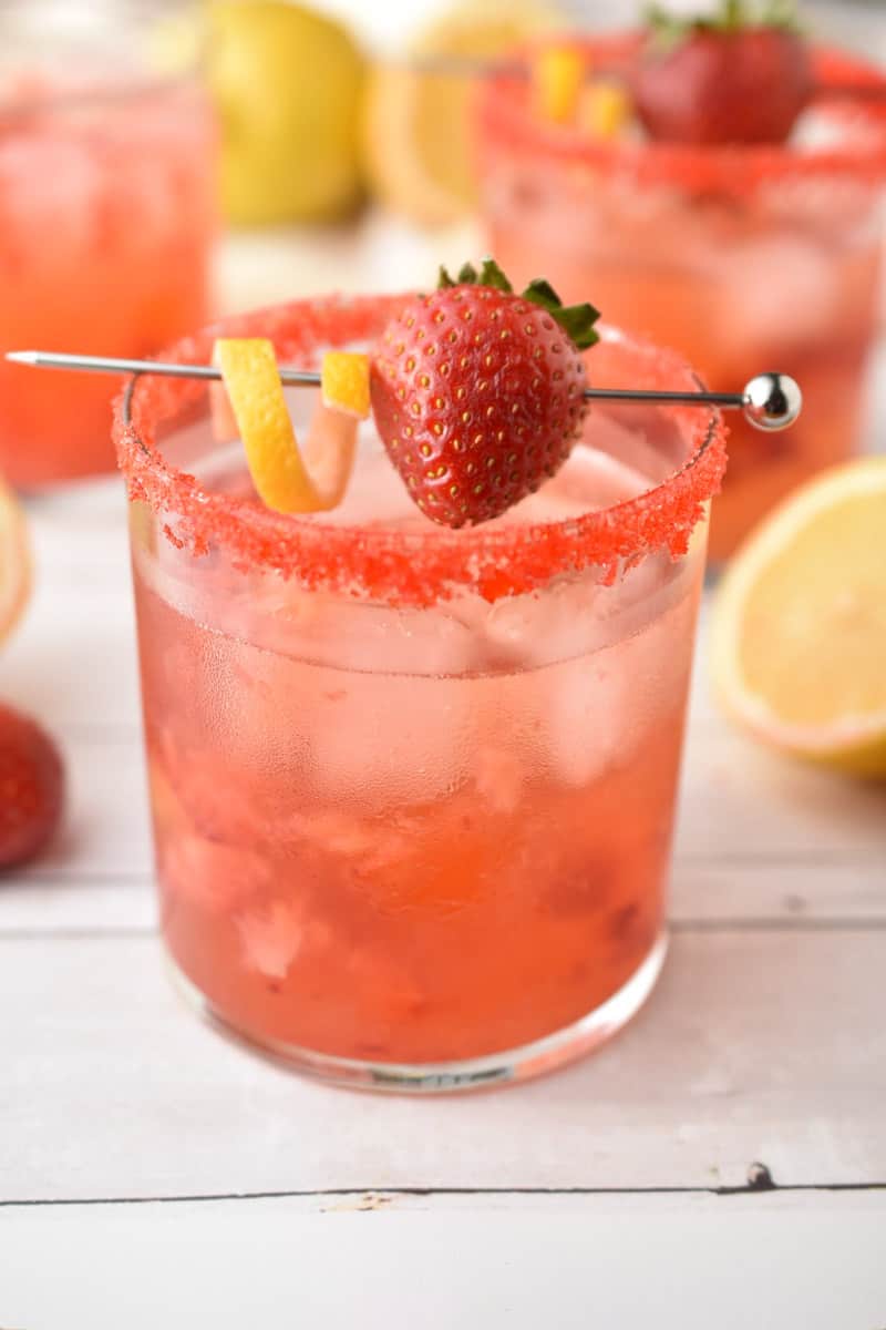 vodka drink with red sugar rim and strawberry lemon garnish.