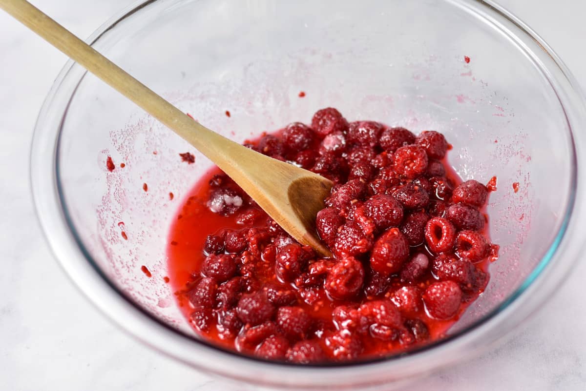 raspberries and cornstarch with lemon juice in a glass bowl.