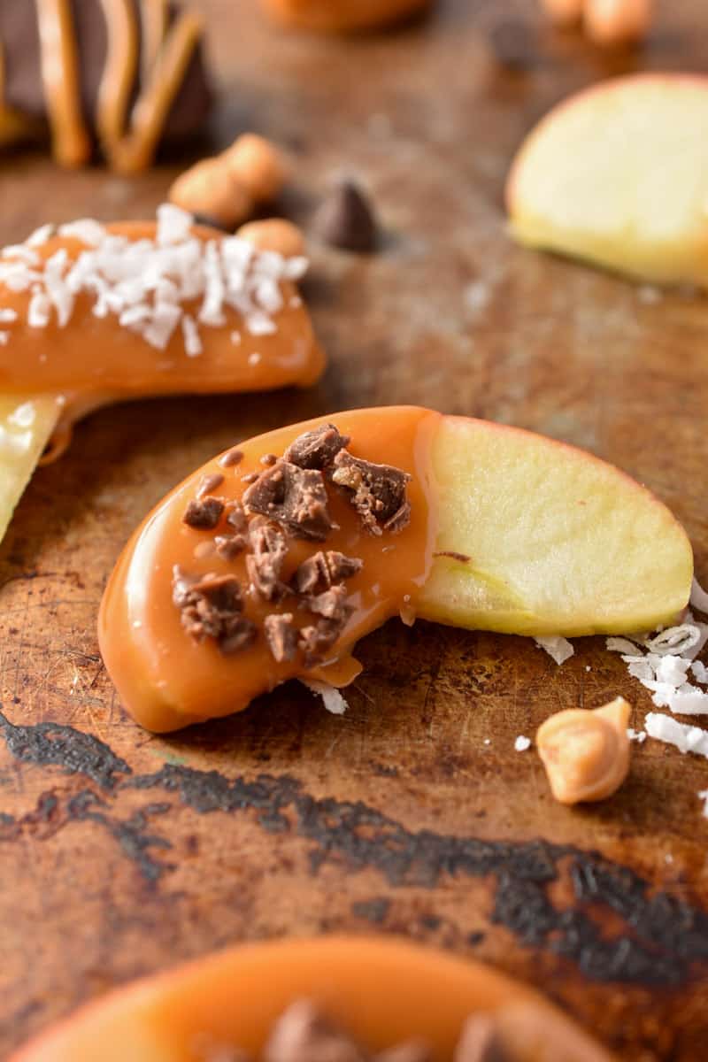 closeup of apple slice coated with caramel and sprinkled with chocolate.