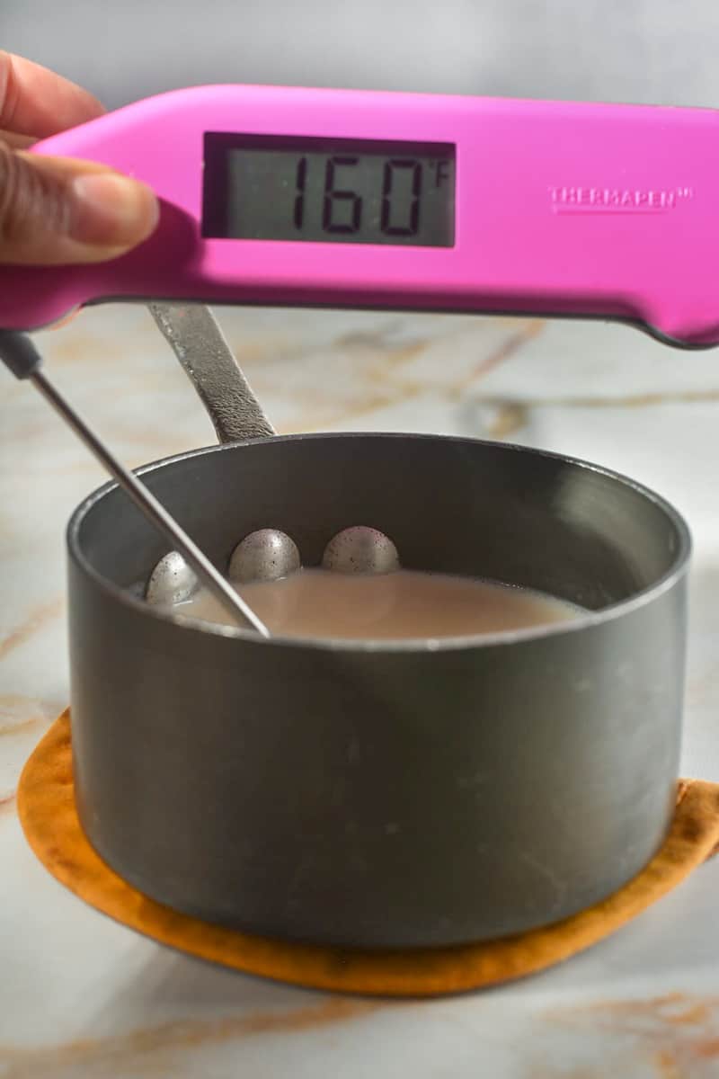 milk in a man with a thermapen reading 160 degrees