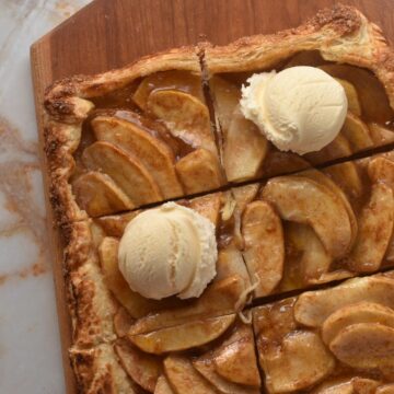 apple galette on cutting board with two scoops of ice cream on top.