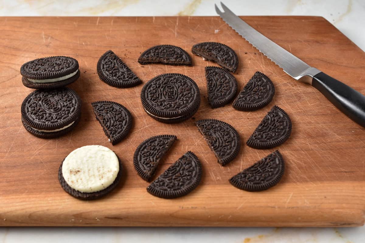 oreo cookies on a cutting board with a serrated knife.