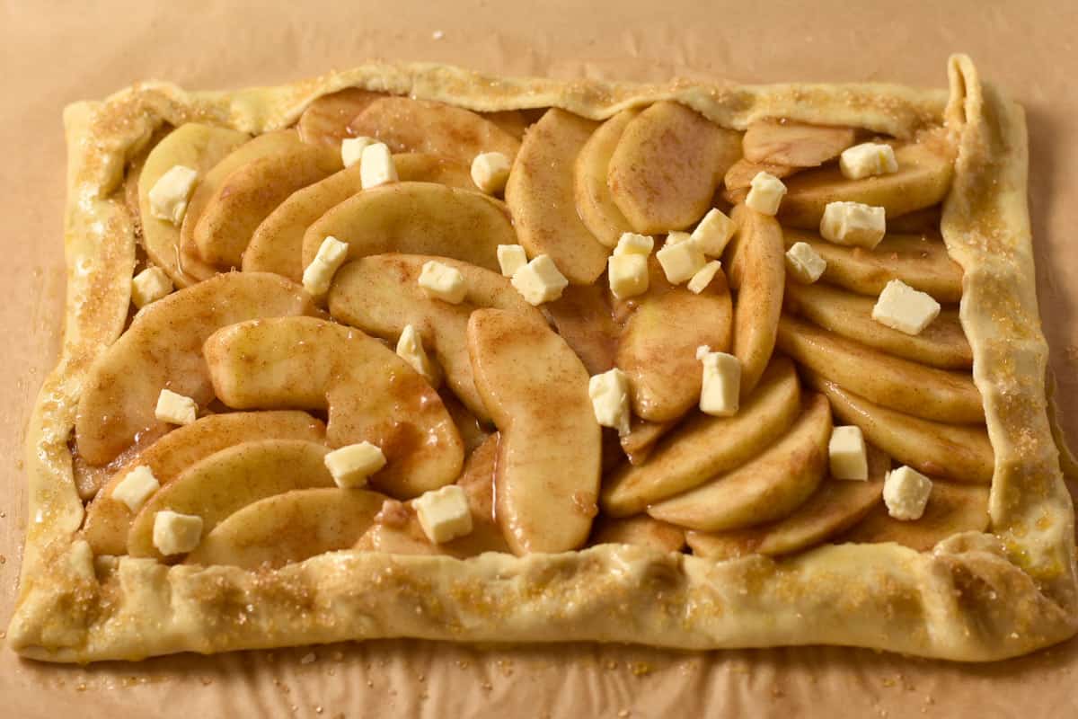 apples in puff pastry crust with butter dotting the crust.