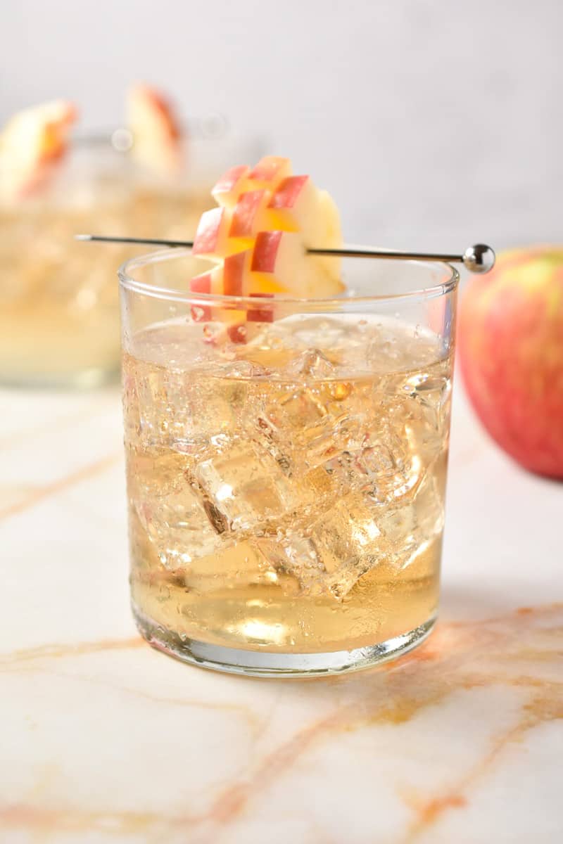 clear low ball glass with drink and apple slice garnish.