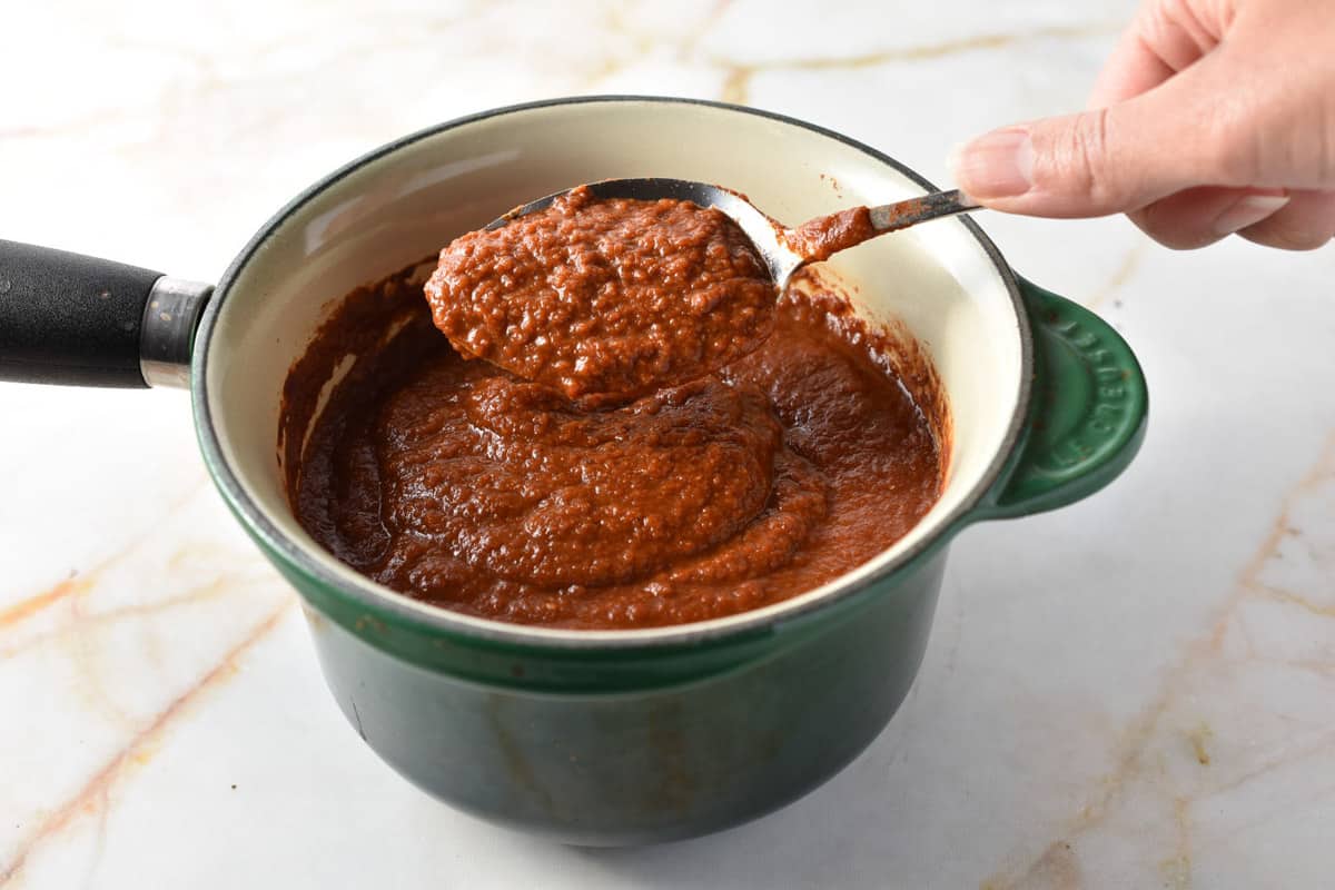 spoon with tex mex paste above a pan sauce. 