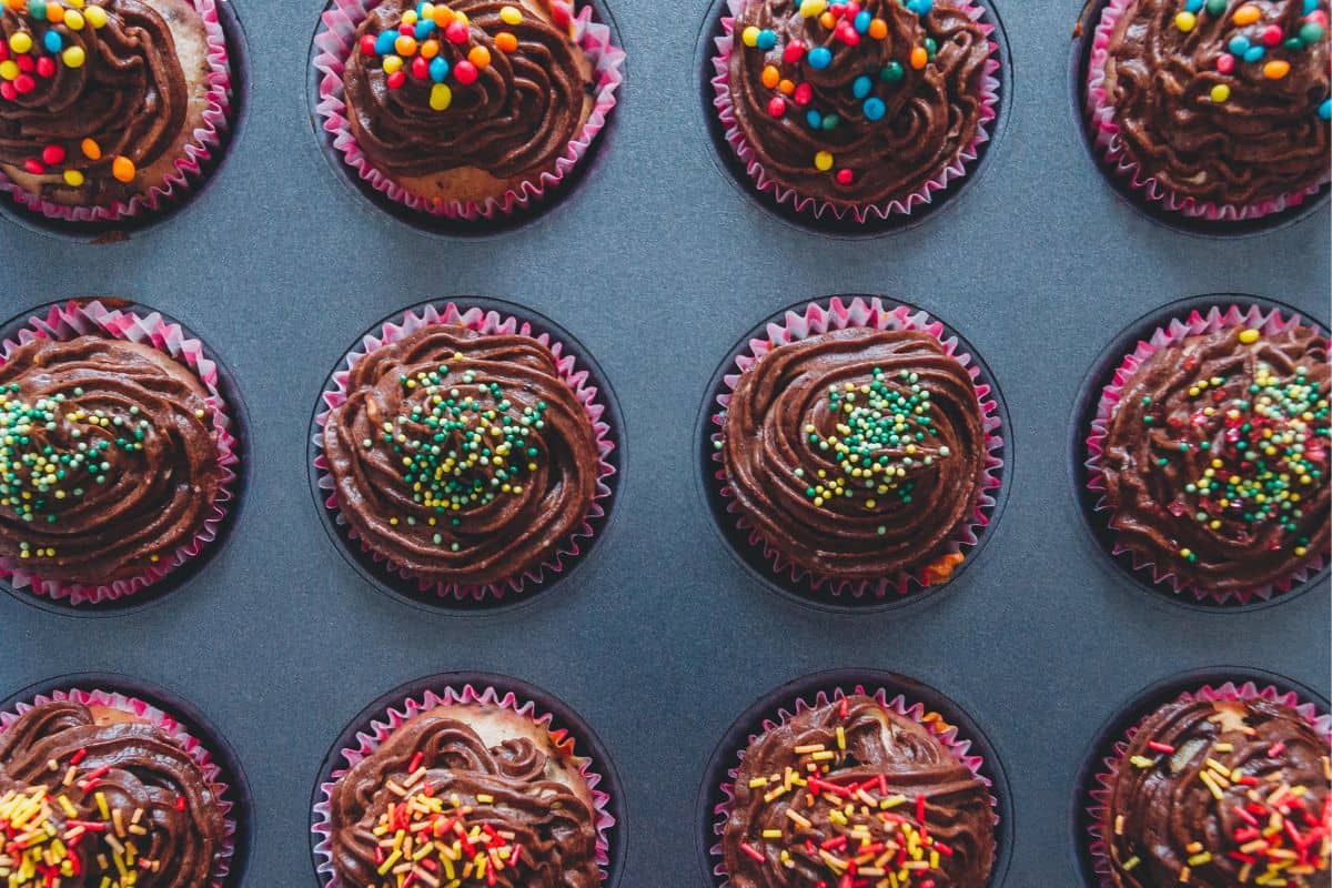 chocolate cupcakes with sprinkles in a metal baking pan. 