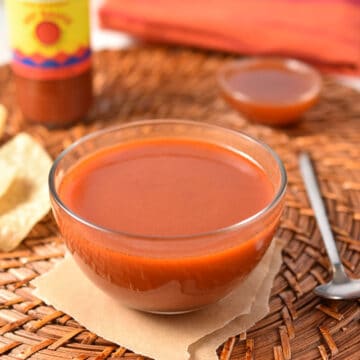sweet heat sauce in a glass bowl with hot sauce in the background.