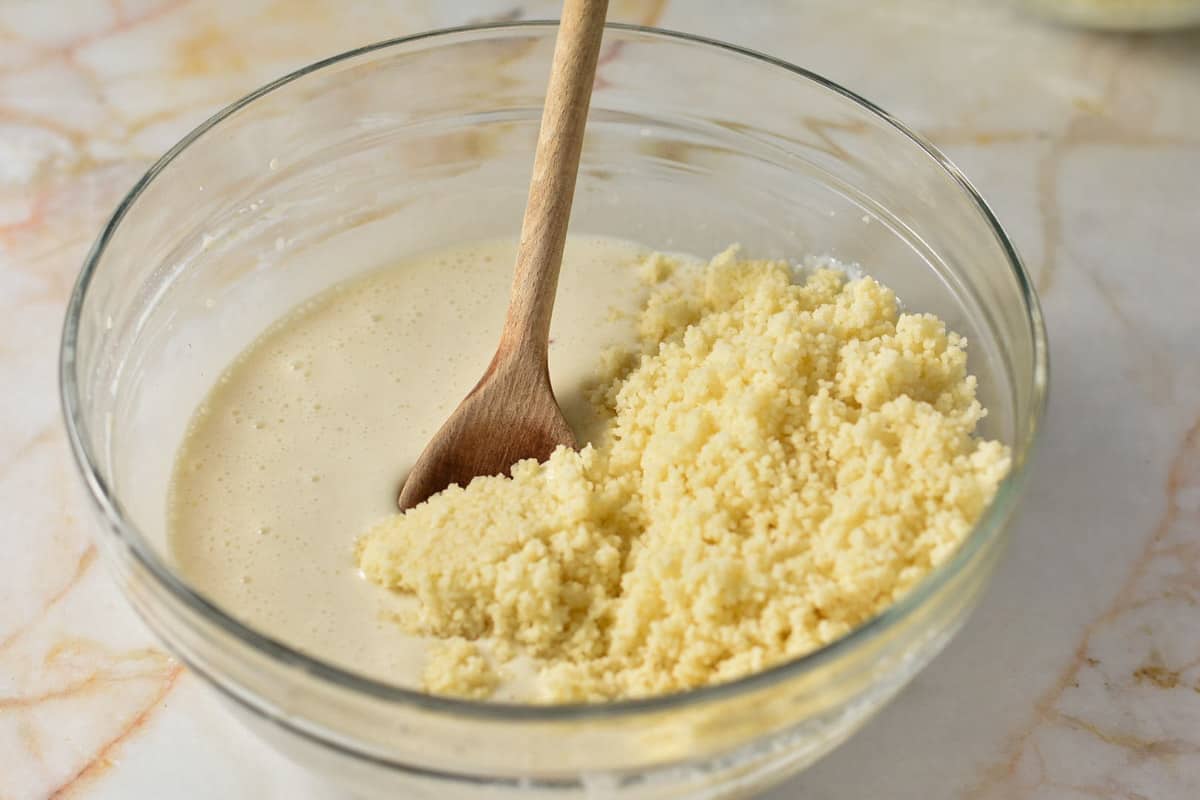 couscous and milk mixture in a glass mixing bowl.