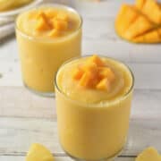 mango-a-go-go smoothie in clear class with pineapple and mangos.