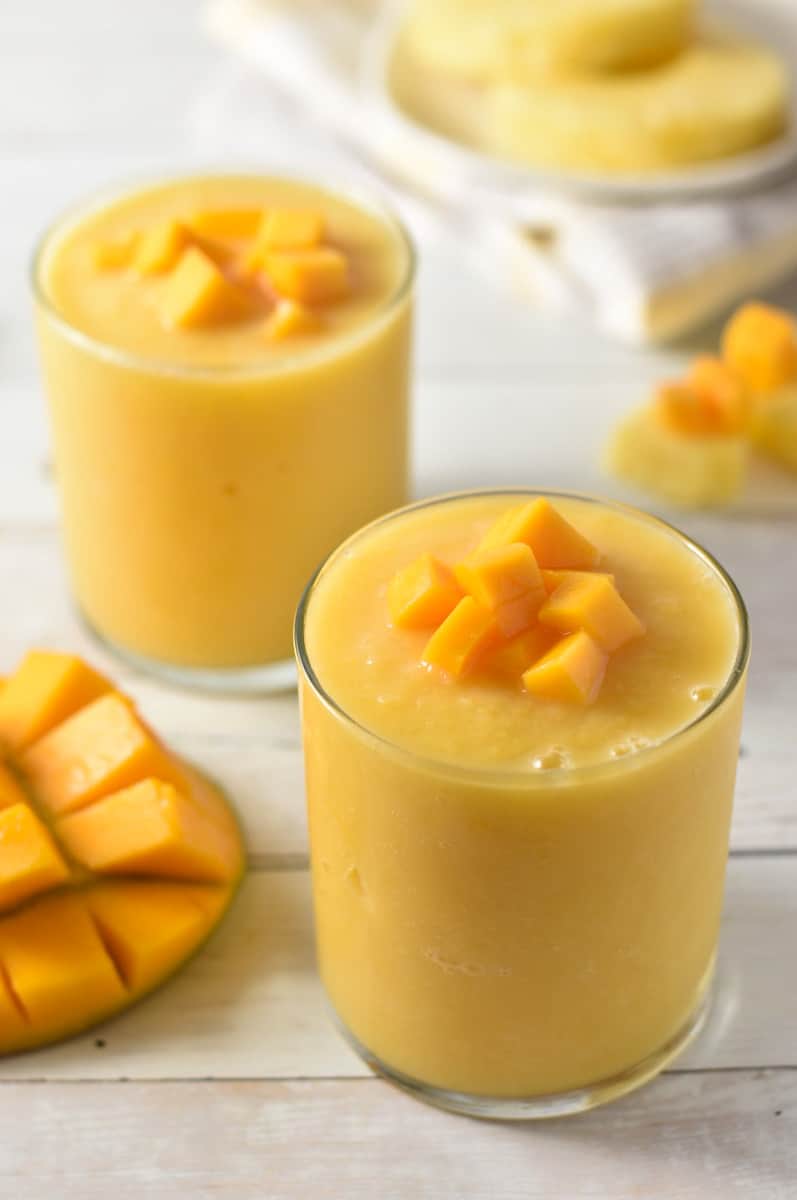 Mango-a-Go-Go Smoothie in glass containers on a wooden counter.