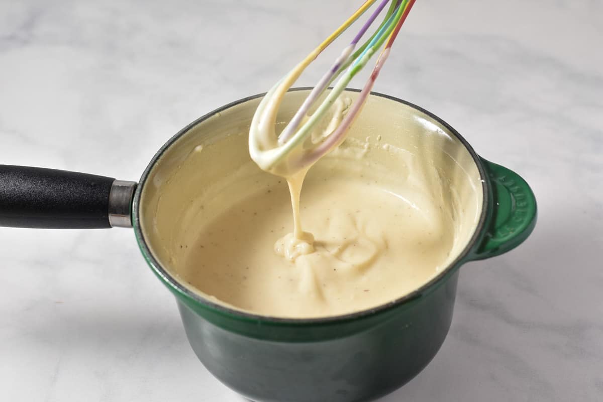 cream sauce being whisked in a pan.