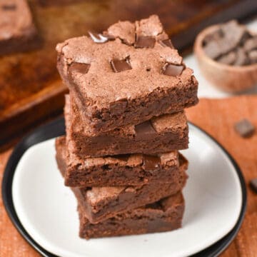 chocolate fudge brownies stacked on a plate.