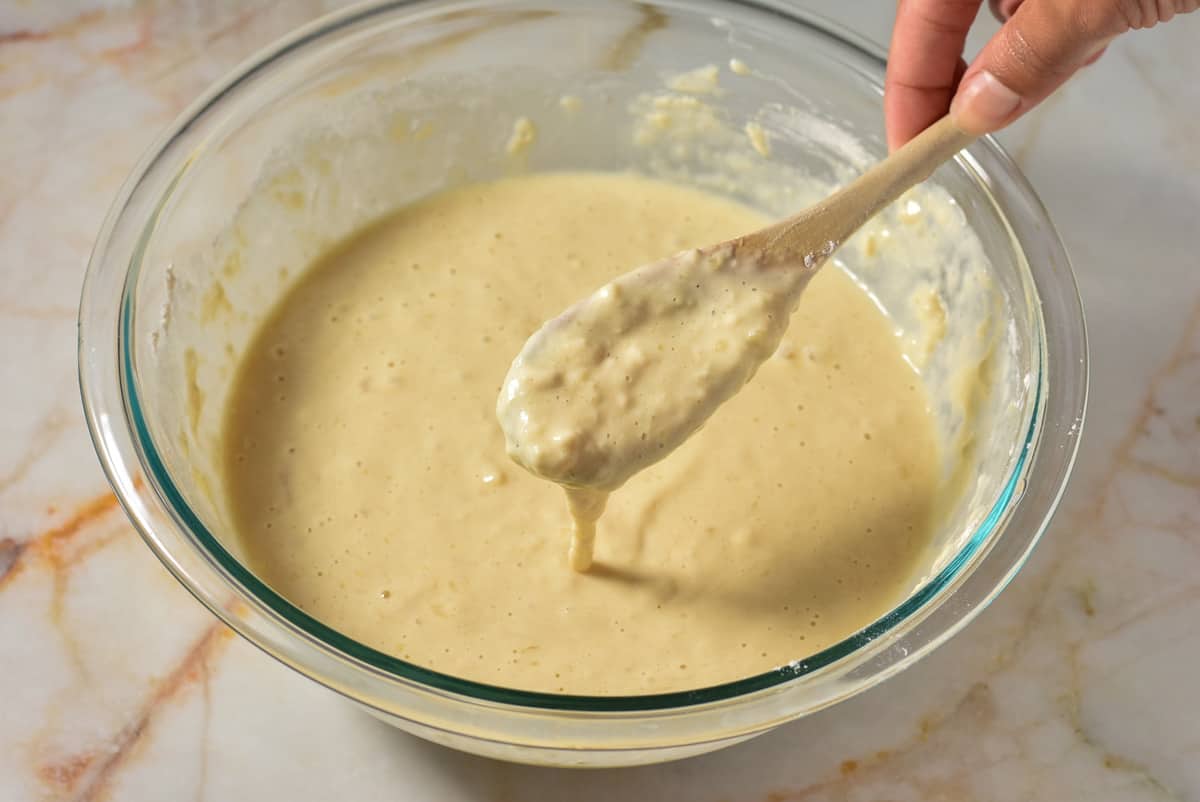 lumpy pancake batter in a bowl with batter dripping off a spoon. 