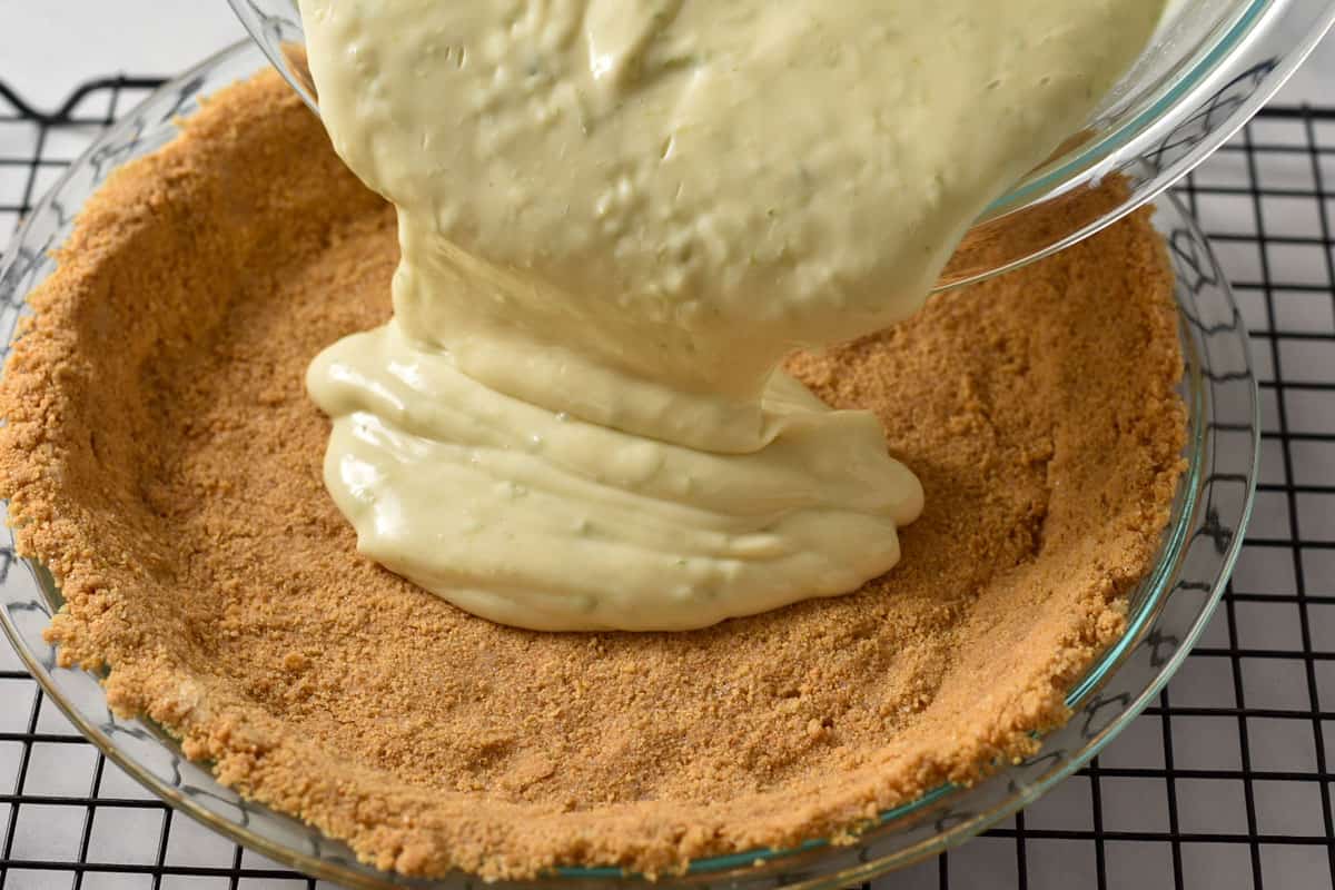pouring key lime pie filling into the prepared graham cracker crust.