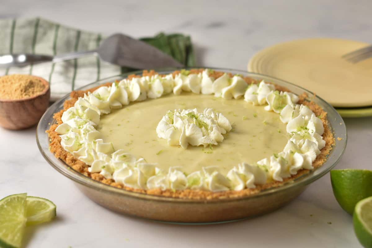 key lime pie fully garnished sitting in pie plate.