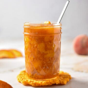 peach compote in a jar with a spoon.