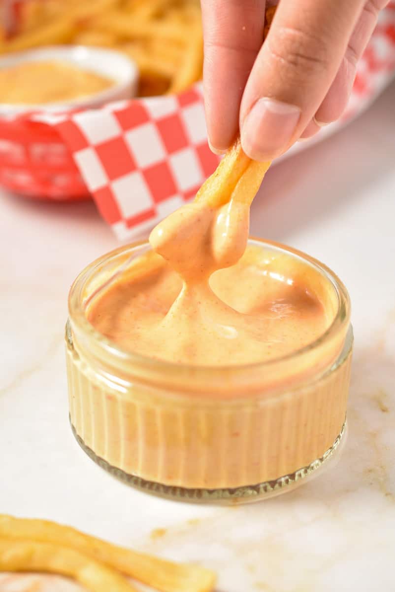 french fries dipped into creamy container of fry sauce. 