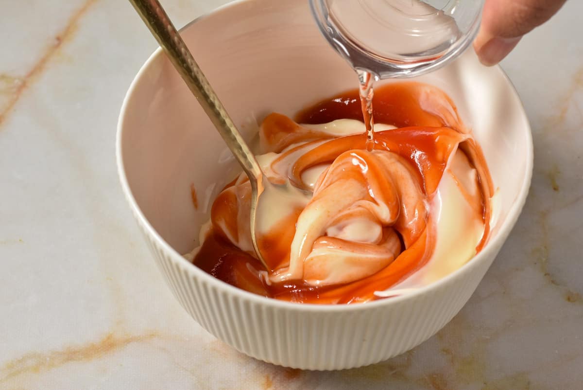 mayo and ketchup in a bowl with vinegar being poured in. 