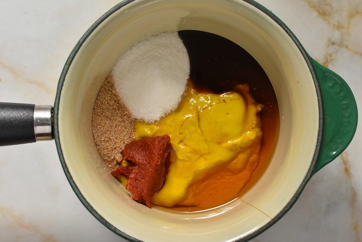 mustard, honey, tomato paste, sugar, and spices in a pot. 