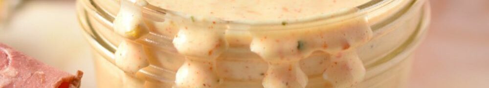 creamy spicy ranch dressing in a bowl with sandwich.